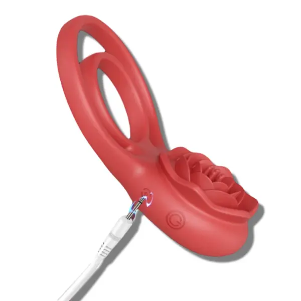 A white charging cable is plugged into the side of the rose penis ring vibrator, showing its rechargeable feature. A soft glow highlights the power button area, indicating active charging.