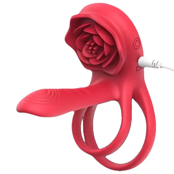 Close-up of a dual vibrating penis ring in red, shaped like a rose, with a charging cable plugged into the side for recharging.