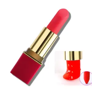 A discreet red lipstick-shaped vibrator with a gold and red casing, designed to resemble a traditional lipstick. In the corner, a close-up shows the silicone tip flexing and slightly melting, hinting at its soft texture and functionality.