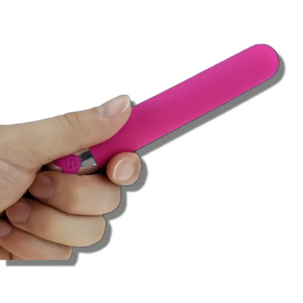 Close-up of a hand holding a pink rechargeable bullet vibrator with a smooth silicone finish and metallic control base.