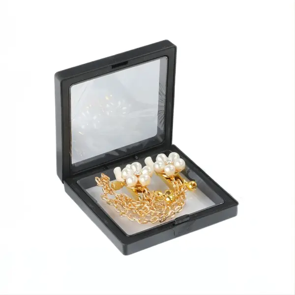 Side view of the sexy pearl nipple clamps inside a black display box, showcasing the connected gold chain coiled beneath the clamps.