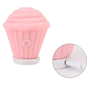 Pink Cupcake Clit Suction Stimulator – Sweet Treat resting on its magnetic charging base with cable connected, ready for wireless recharging.