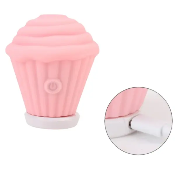 Pink Cupcake Clit Suction Stimulator – Sweet Treat resting on its magnetic charging base with cable connected, ready for wireless recharging.