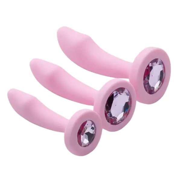 Three silicone Pink Curved Butt Plug-Cherry Velvet pieces in small, medium, and large sizes are arranged side by side. Each features a faceted gem set into the flared base, showcasing the smooth curved shaft and rosy pink finish.