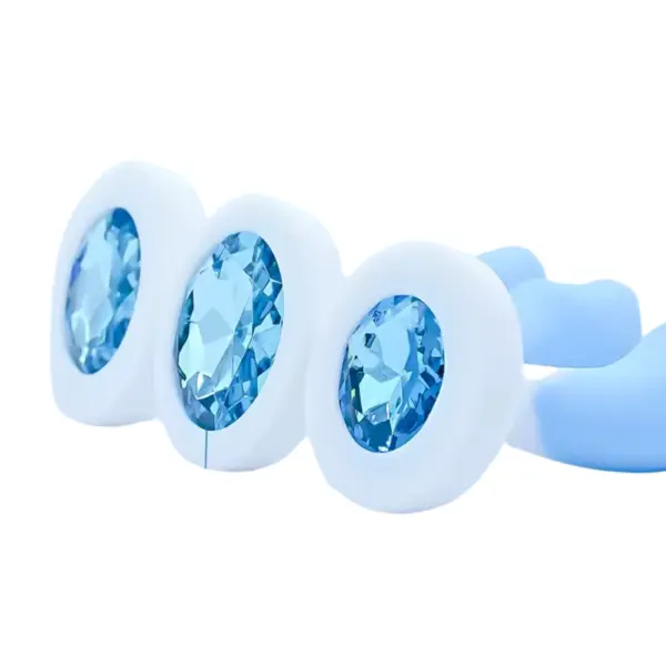 Close-up of the Blue and White Silicone Plug-Gentle Vice flared bases, each set with a faceted translucent blue gem. The detailed shot emphasizes the glossy jewel accent against the matte white silicone for an elegant, wearable design.