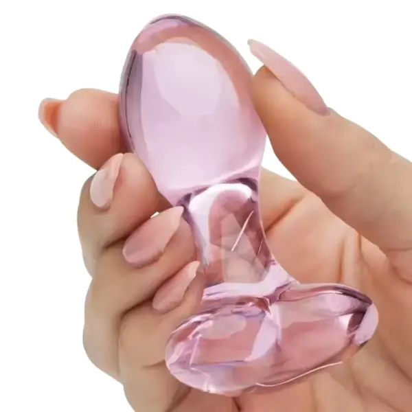 Glass heart shaped butt plug Love Vice held in a hand to demonstrate its size, weight, and ergonomic glass design