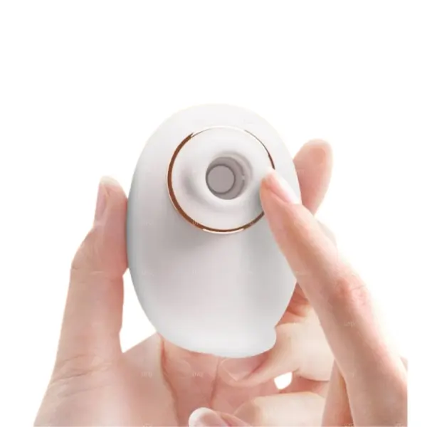 Close-up of a fingertip pressing into the top of the white cat-shaped silicone head of the Kitty Swirl, showing its pliable, soft-touch texture.