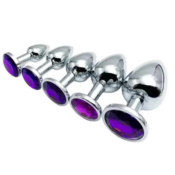 Lined up smallest to largest, five metallic silver butt plugs with purple gem-topped bases displayed side by side on a white background.