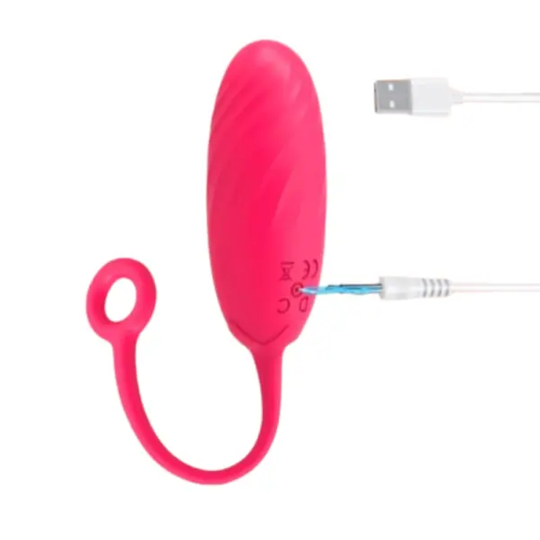 Pink Wireless Egg Vibrator – BlushPop being charged with a USB cable, plugged into the silicone charging port on the base of the toy.