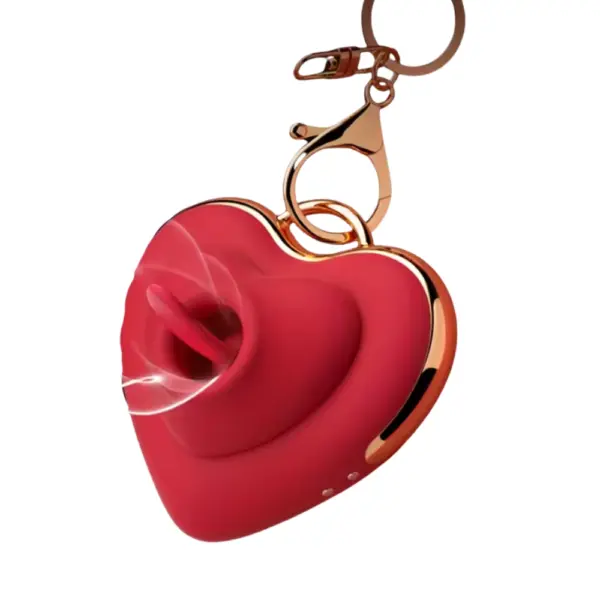 Side view of the Heart Flutters keychain vibrator in red, demonstrating the licking function with a tongue-like silicone tip emerging from the central suction hole, gold clasp detail visible.