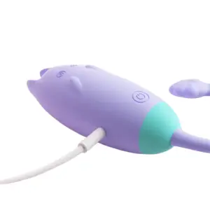 Side view of the Remote Control Kitty Love Egg – PurrVibes while charging via a USB cable, highlighting the silicone charging port and ergonomic form.