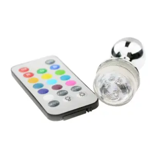 The LED Light Butt Plug – Booty Glow lying next to its remote control, highlighting the transparent LED cap and internal chip design.