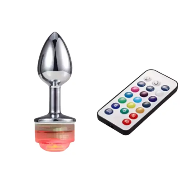 The LED Light Butt Plug – Booty Glow standing upright with its base glowing red, positioned beside the multi-color remote for brightness and mode control.
