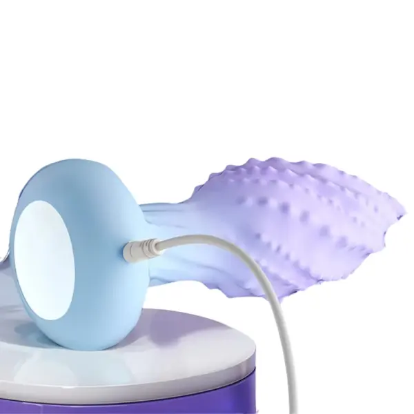 Rotating Butt Plug – Cheeky Twirl displayed on a flat surface while charging, showing the flexible ridged design and a white USB cord plugged into its pastel blue base.