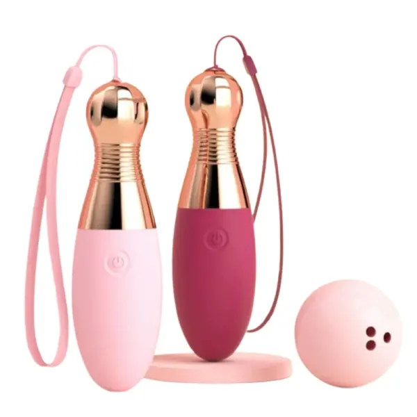 Two Strikella vibrators in soft pink and deep rose colors standing upright beside a pastel pink bowling ball and charging base, highlighting the playful theme.