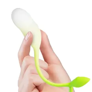 A hand holding the Verdanta vibrator by its white silicone egg, showing its petite size and the green leaf-shaped tail curving naturally.