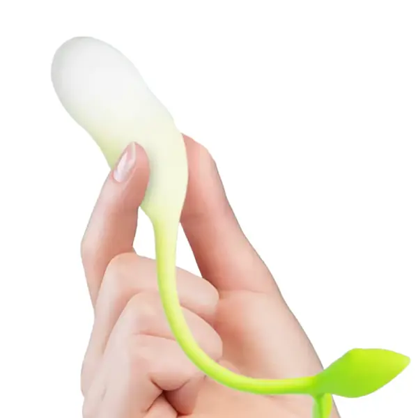 A hand holding the Verdanta vibrator by its white silicone egg, showing its petite size and the green leaf-shaped tail curving naturally.