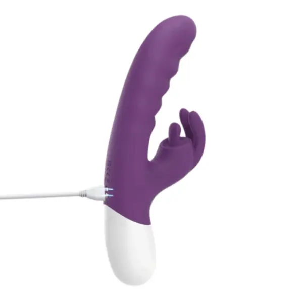 Close-up of the VoltBloom rabbit vibrator connected to a USB charging cable, showing the seamless purple silicone body and white plastic base.