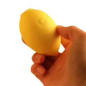 Lemon Shaped Suction Vibrator – Citric Lust being gently squeezed between thumb and fingers without the cap to show its compact size and soft silicone texture.
