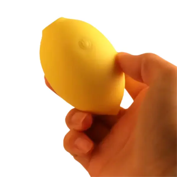 Lemon Shaped Suction Vibrator – Citric Lust being gently squeezed between thumb and fingers without the cap to show its compact size and soft silicone texture.