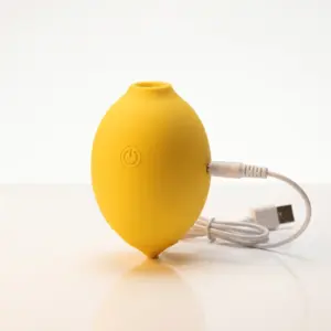 Close-up image of the Lemon Shaped Suction Vibrator by Citric Lust with a charging cable inserted, highlighting the rechargeable design and smooth finish.
