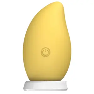 MangoTango clitoral vibrator standing vertically on a white charging base, featuring a soft yellow mango-shaped design with a central power button.