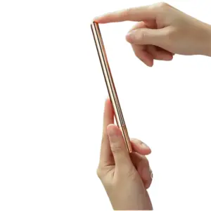 Close-up of hands holding the GleamLine slim gold wand, showing its smooth metal body and elegant tapered tip.